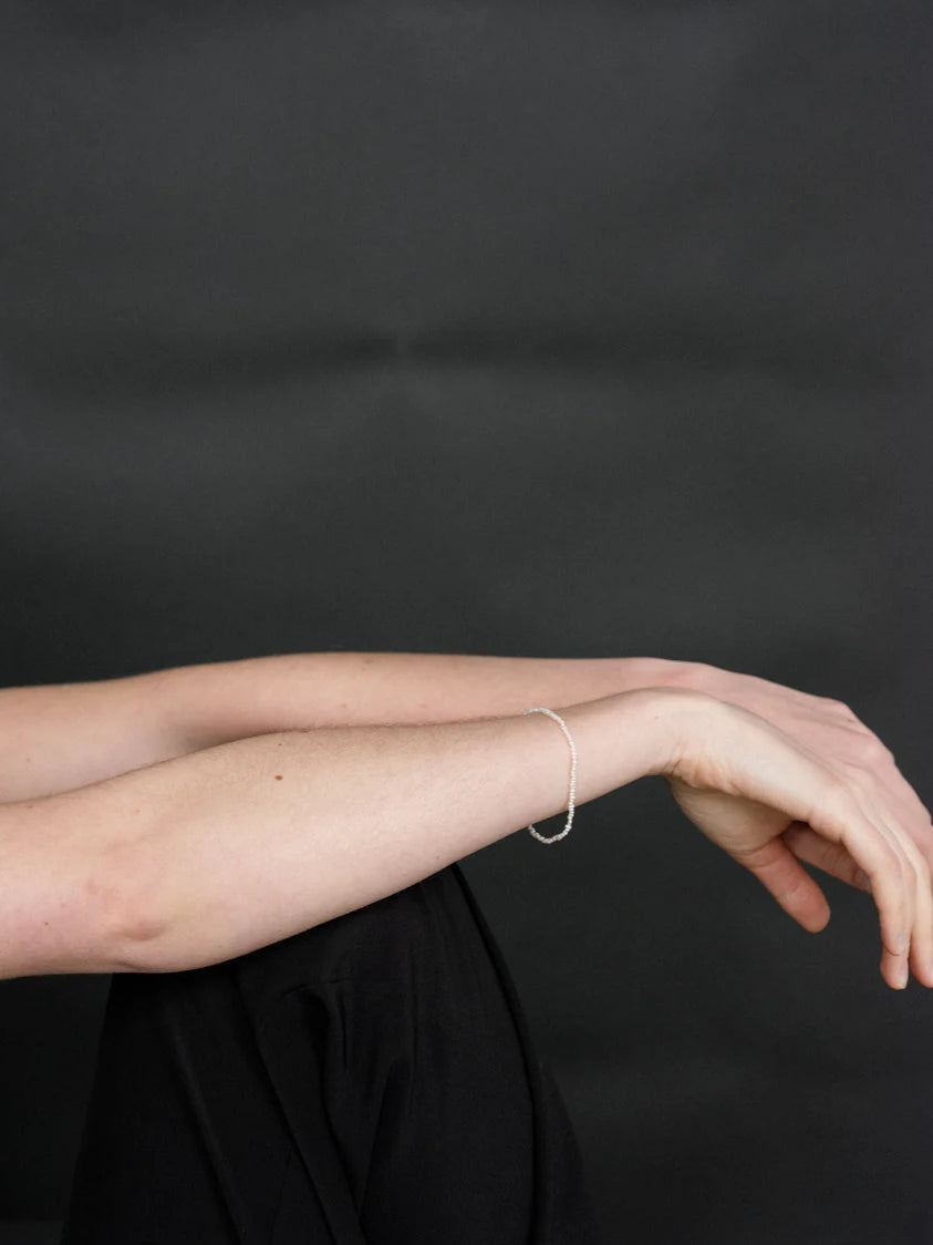 Person wearing a thin strand pearl bracelet.